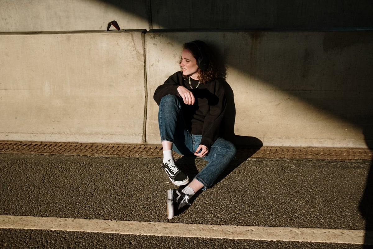 Woman in Black Jacket and Blue Denim Jeans Sitting on Concrete Stairs